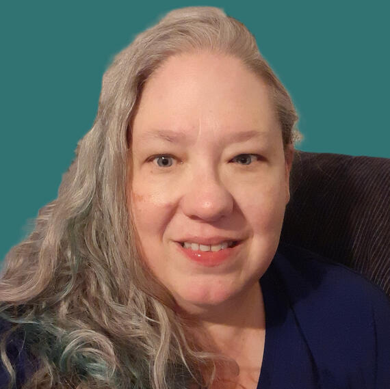 Me- Romill A caucasion woman with long hair that transitions into teal at the bottom.